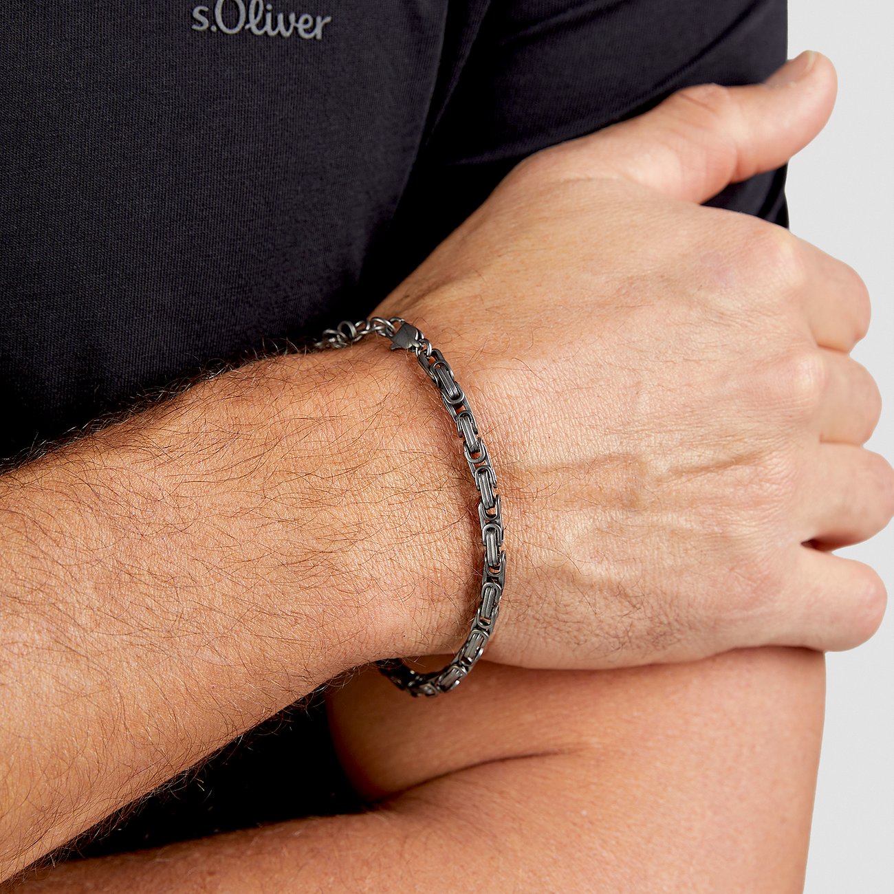 Bracciale s.Oliver re in acciaio inox antracite indossato al polso di un uomo con chiusura a moschettone lucida.