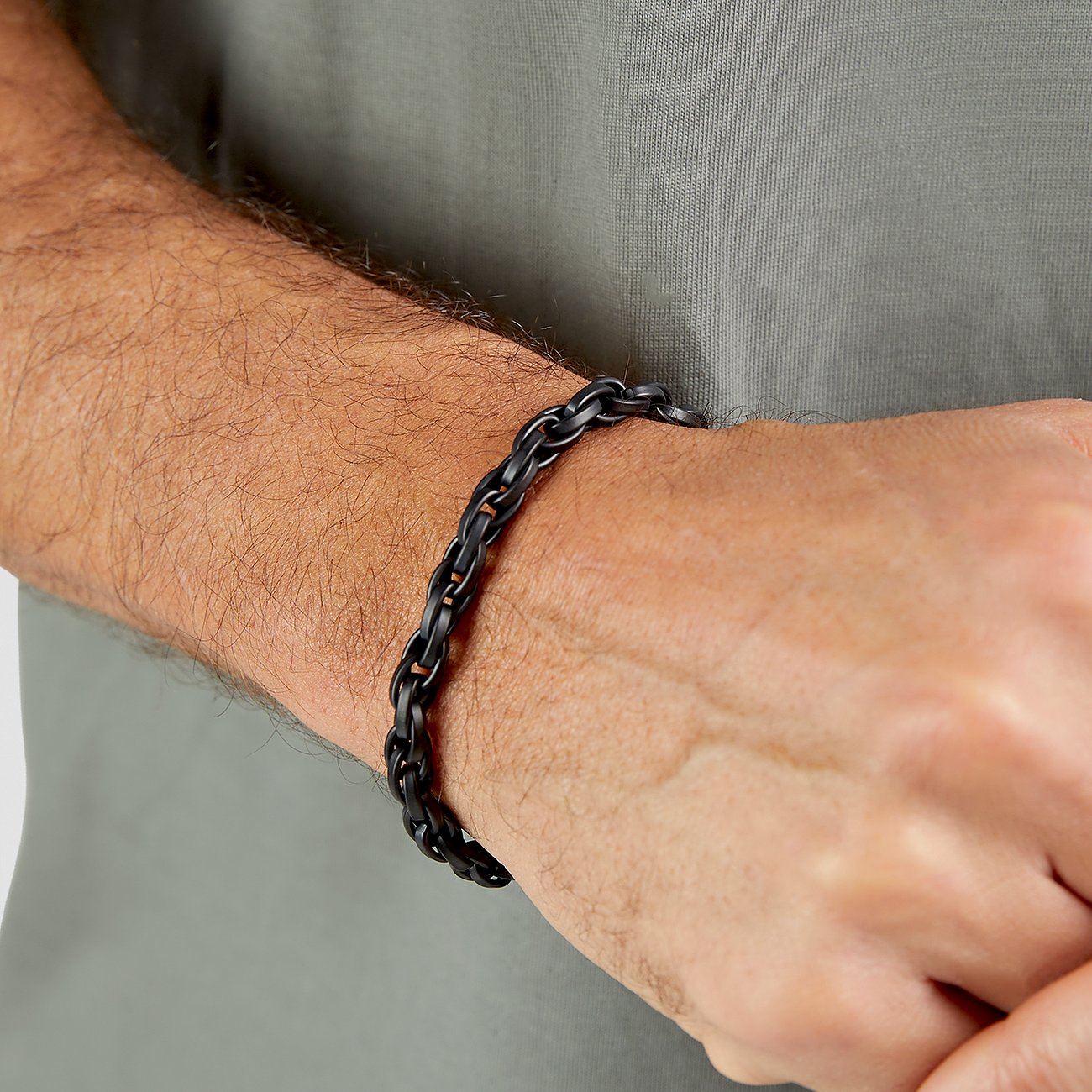 Am Handgelenk eines Mannes ein schwarzes s.Oliver Edelstahl-Armband mit Kettengliedern, aufgenommen leicht von oben.
