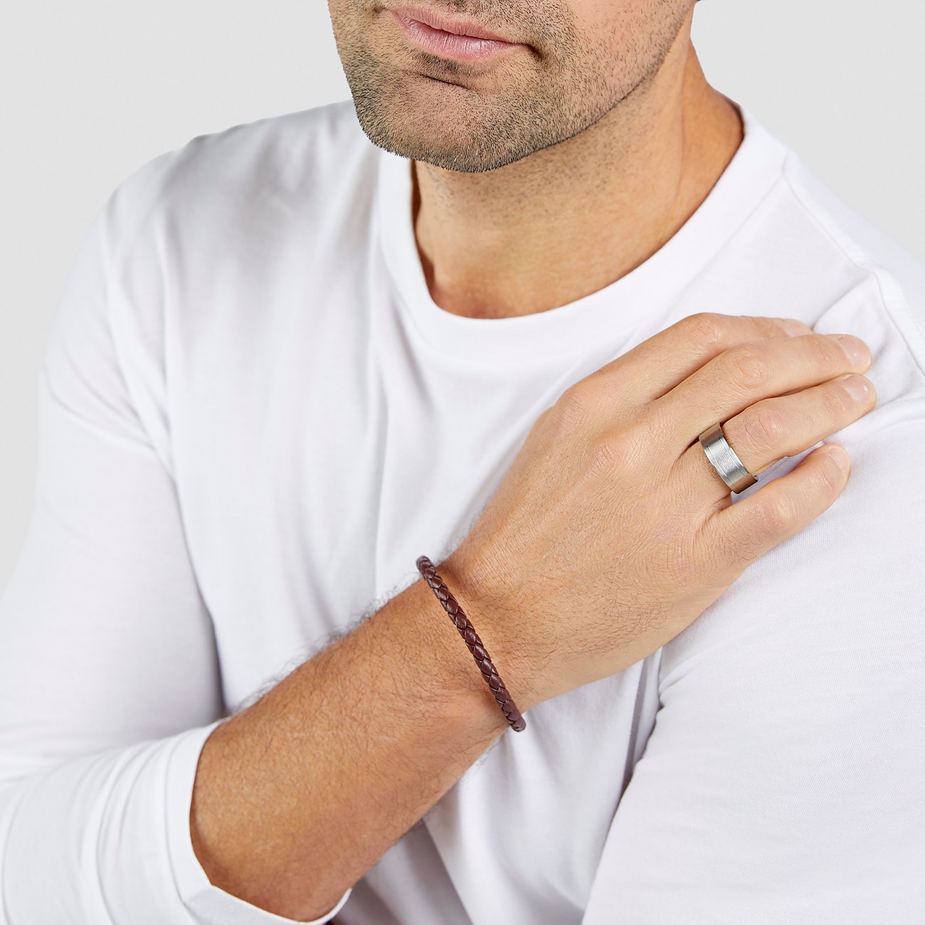 Nahaufnahme eines Mannes, der ein s.Oliver Armschmuck aus geflochtenem braunem Leder trägt.