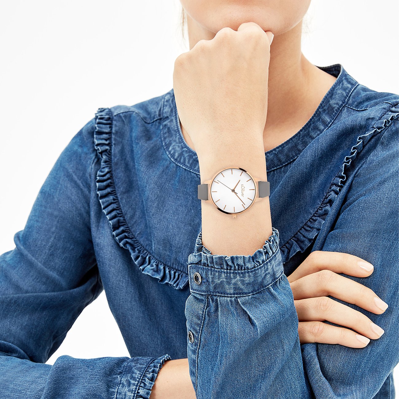 Gros plan sur la montre en métal s.Oliver pour femme, avec bracelet gris et cadran blanc, portée au poignet.