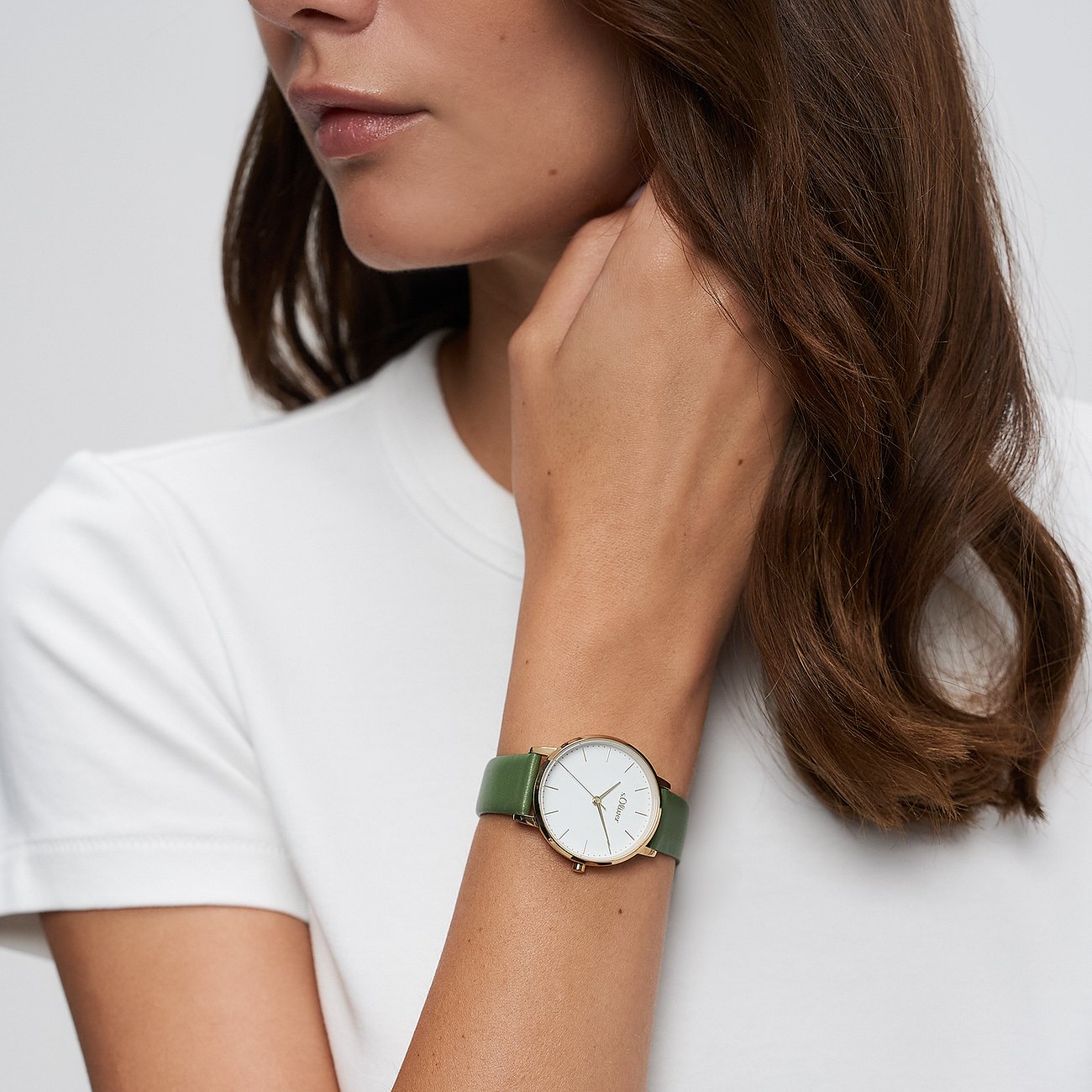 Nahaufnahme einer s.Oliver Damenuhr aus Metall am Handgelenk eines Models. Mattgrünes Lederarmband, weißes Zifferblatt.
