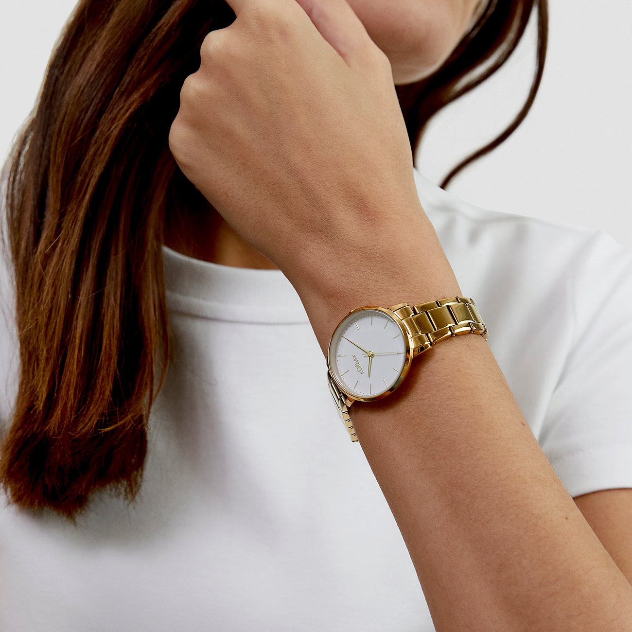 Un orologio da donna s.Oliver con cinturino in metallo dorato e quadrante bianco è indossato al polso sinistro.