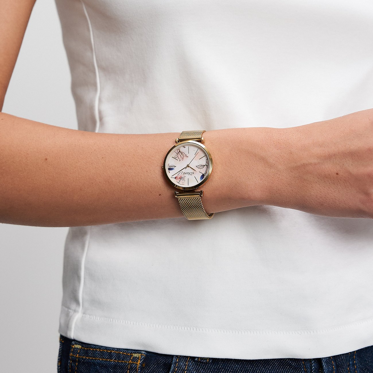 Une montre femme s.Oliver en métal doré avec un cadran clair et des accents floraux au poignet.