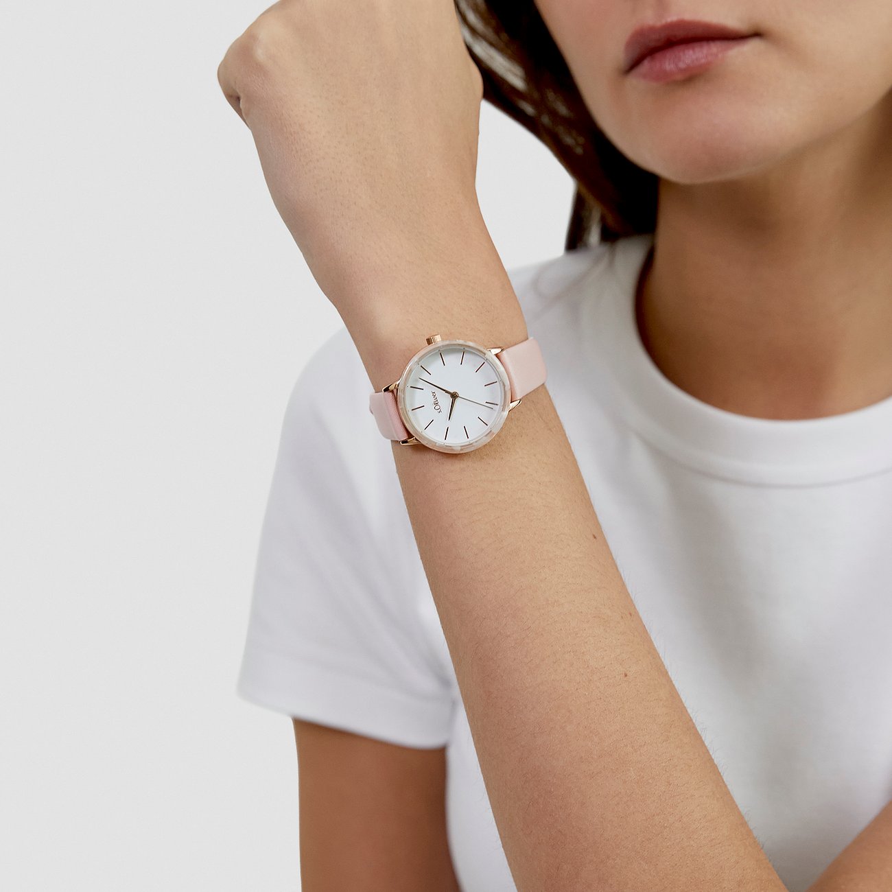 Femme porte une montre s.Oliver ronde en métal avec bracelet en acétate rose au poignet.