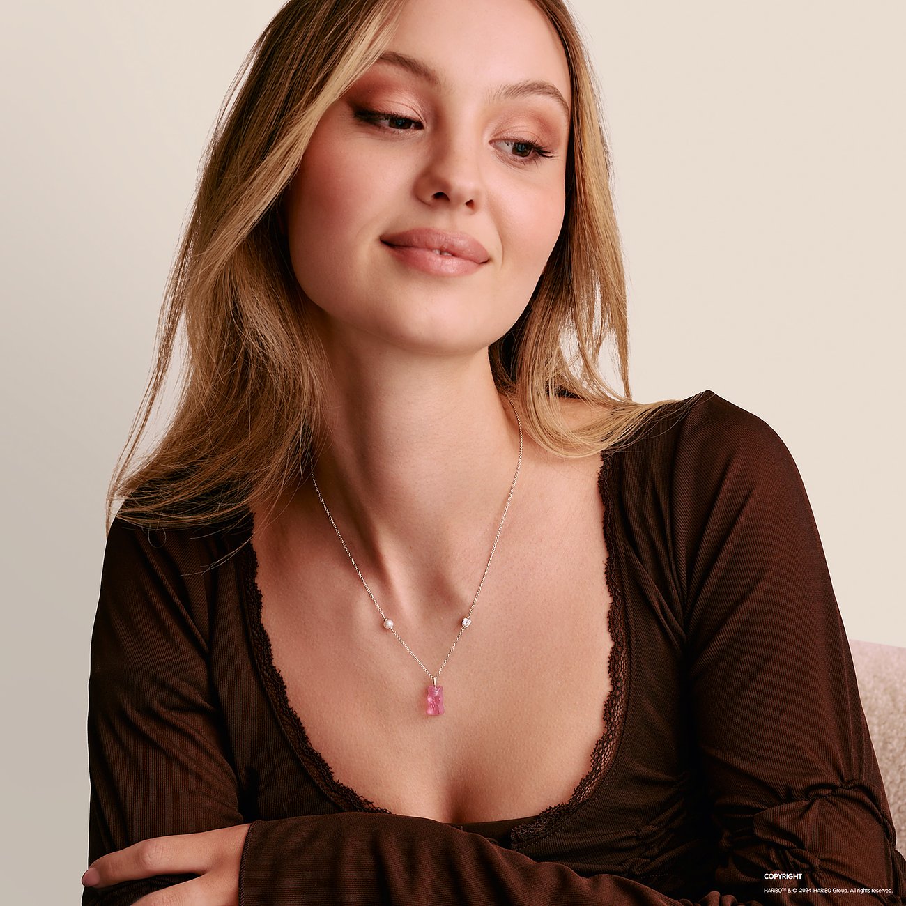 Eine Frau trägt eine silberne Thomas Sabo Halskette mit einem rosa Gummibärchen-Anhänger aus Glasstein.