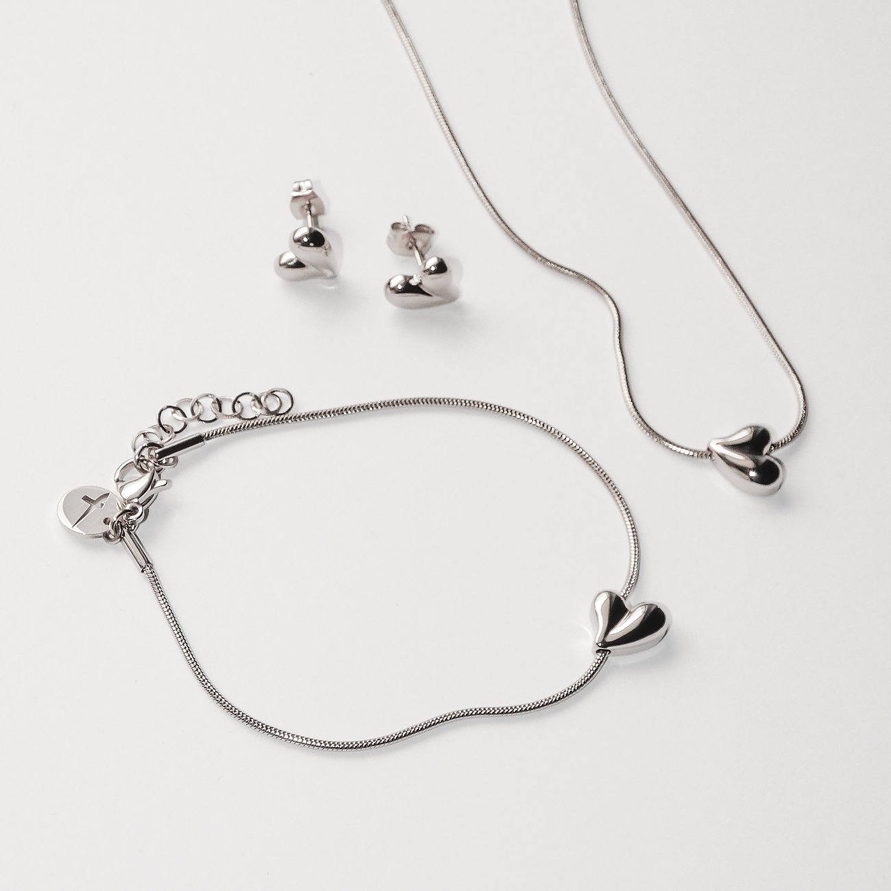 Tamaris Armschmuck und Halskette aus Edelstahl mit Herzanhängern und passende Herzohrstecker.