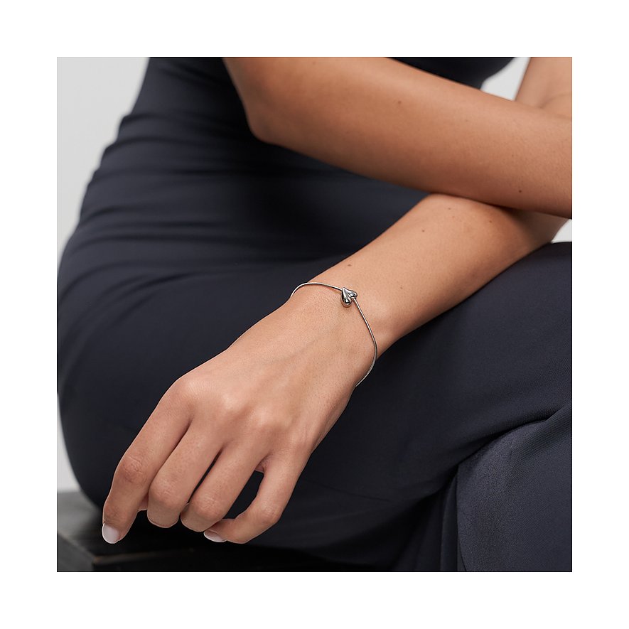 Ein Tamaris Armreif aus Edelstahl am Unterarm einer Person. Der Armreif zeigt ein kleines, poliertes Herz.