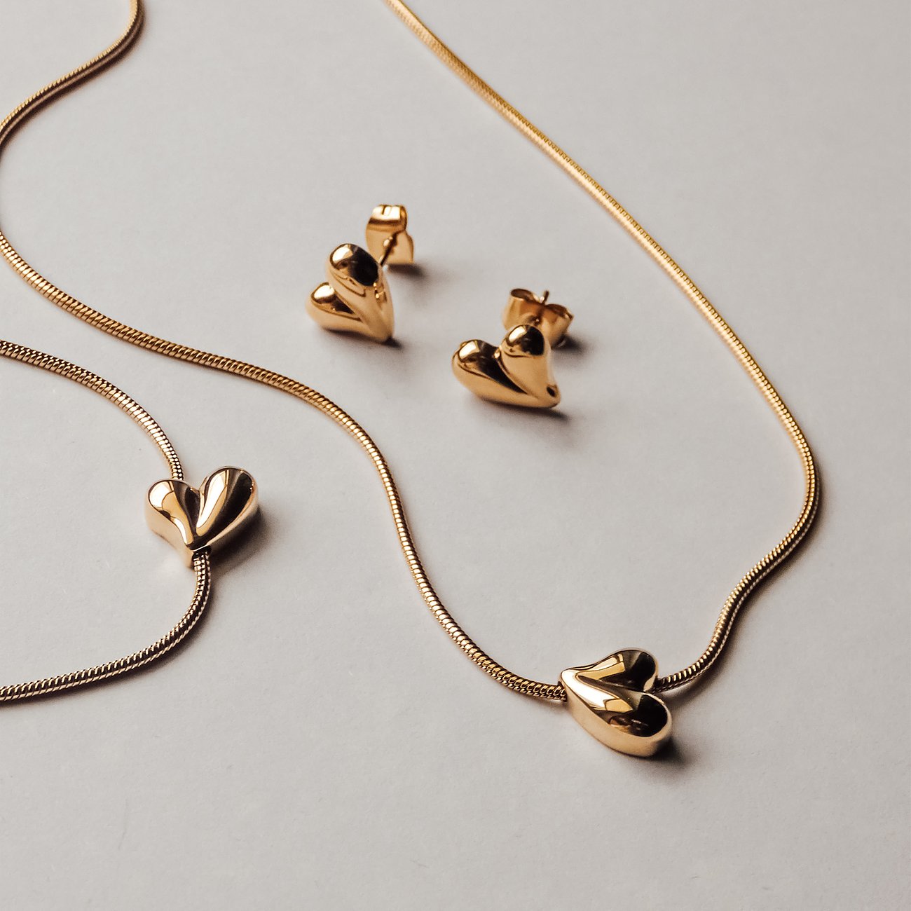 Die Tamaris Armschmuck-Set aus vergoldetem Edelstahl umfasst eine Kette, ein Armband und Ohrstecker mit Herzmotiven.