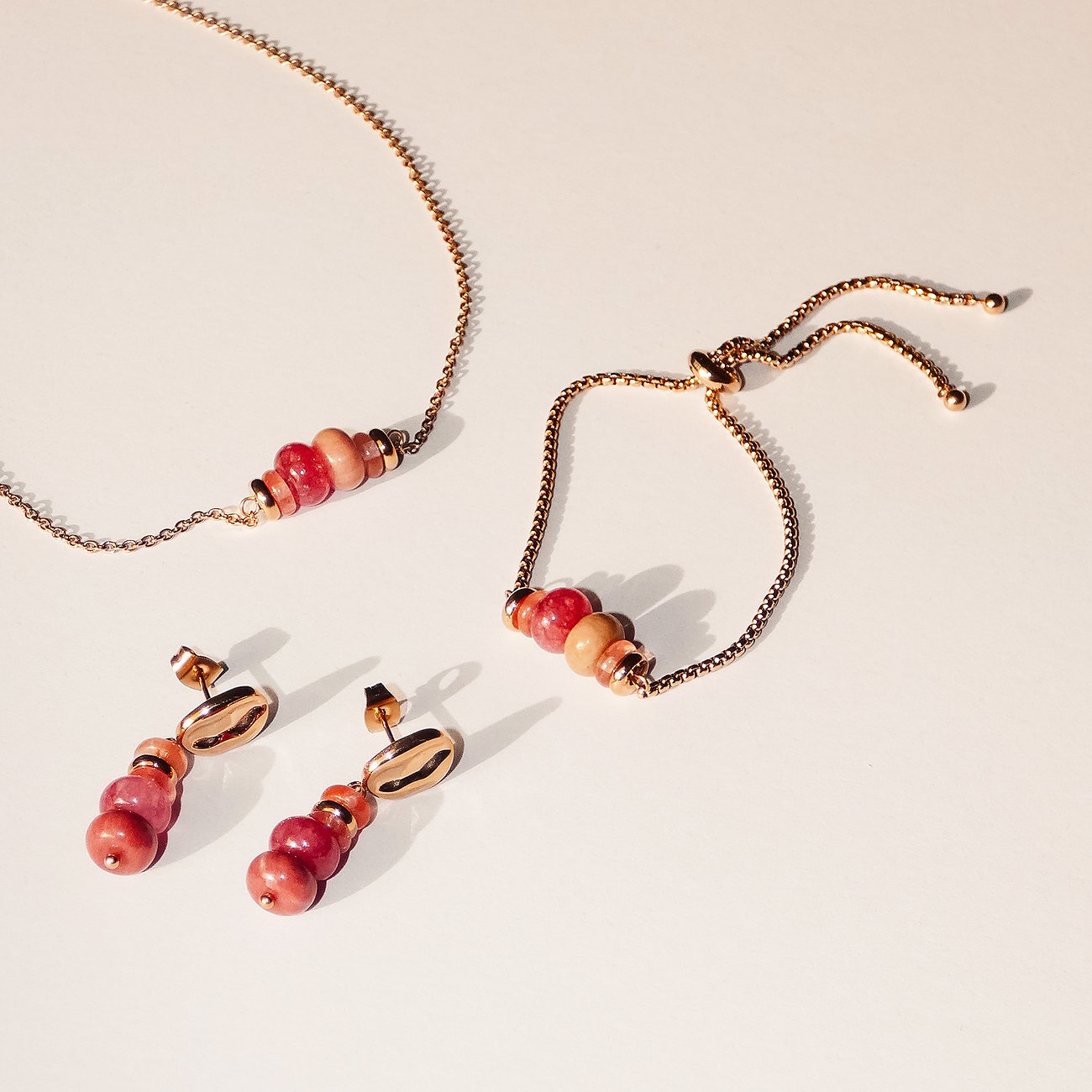 Tamaris Schmuckset aus goldfarbenem Edelstahl: Armband, Kette mit hellrosa/pinken Rhodonit-Farbsteinen & passende Ohrringe.