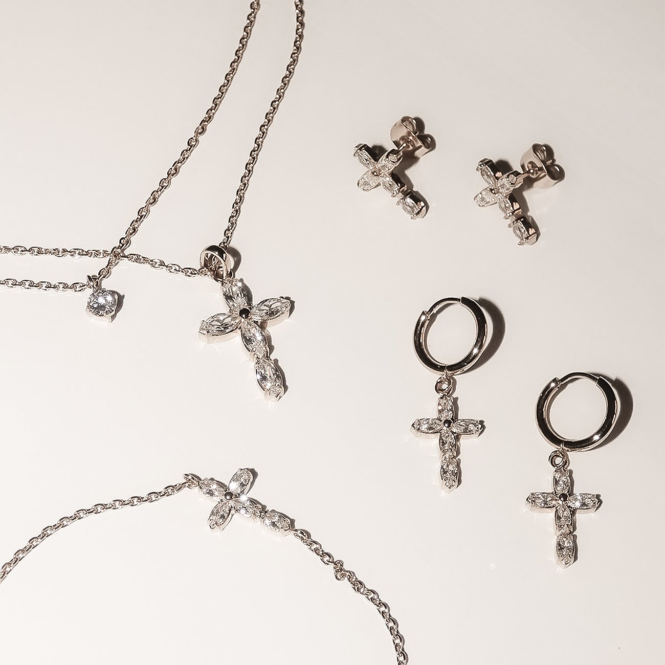Eine Nahaufnahme eines silbernen Tamaris Schmucksets aus Edelstahl mit Kreuzanhängern und Zirkonia Farbsteinen.