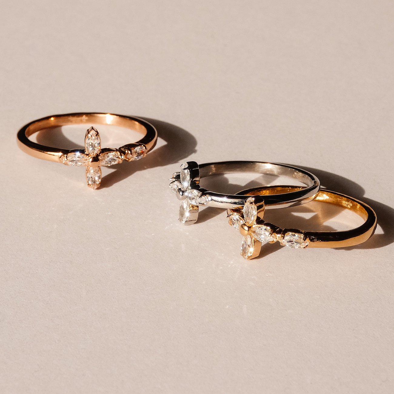 Drei Tamaris Ringe aus Edelstahl in Gold, Roségold und Silber, besetzt mit kreuzförmigen Zirkonia-Farbsteinen.