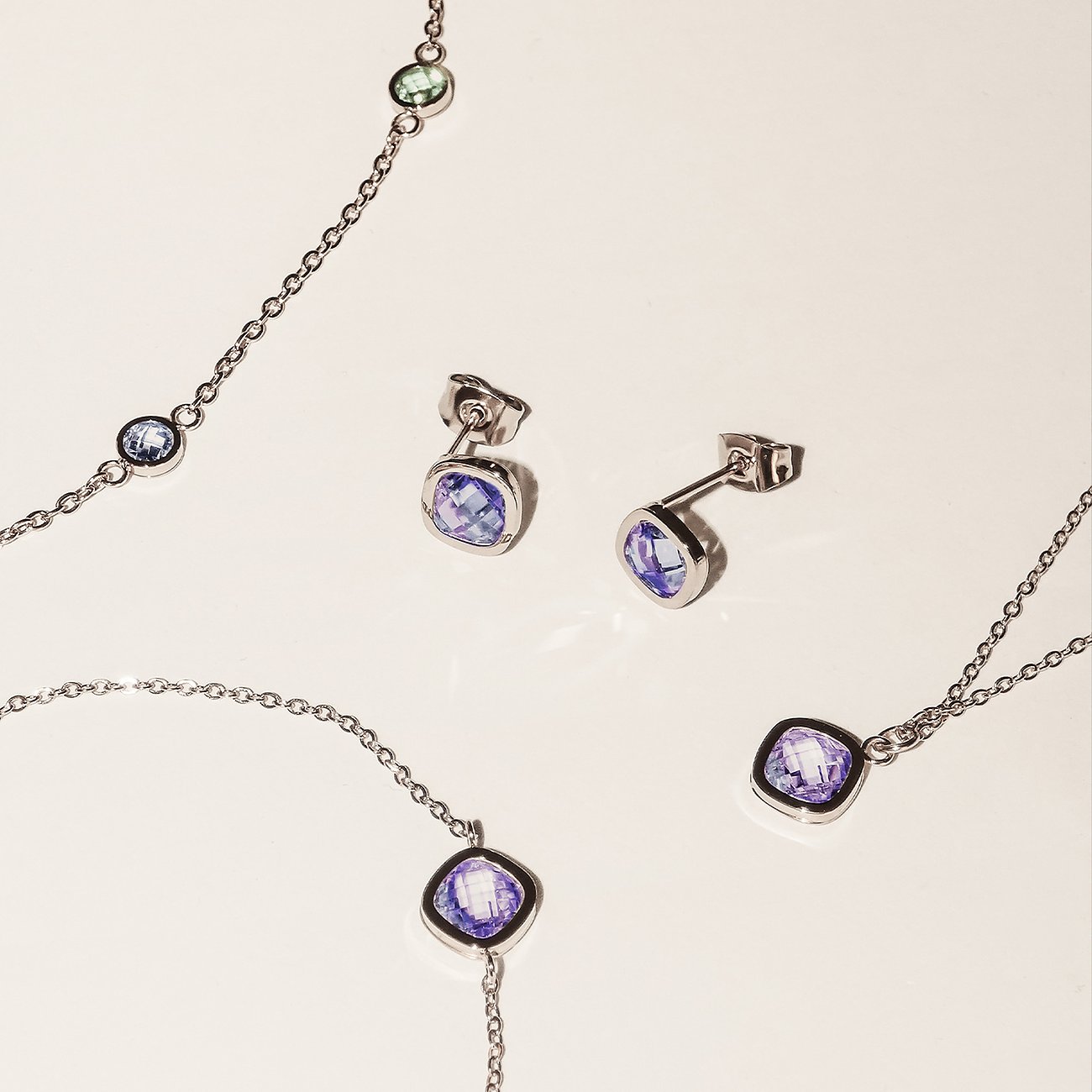 Nahaufnahme eines Tamaris Halsschmucks und Ohrringen aus Edelstahl mit violetten Zirkonia-Farbsteinen.