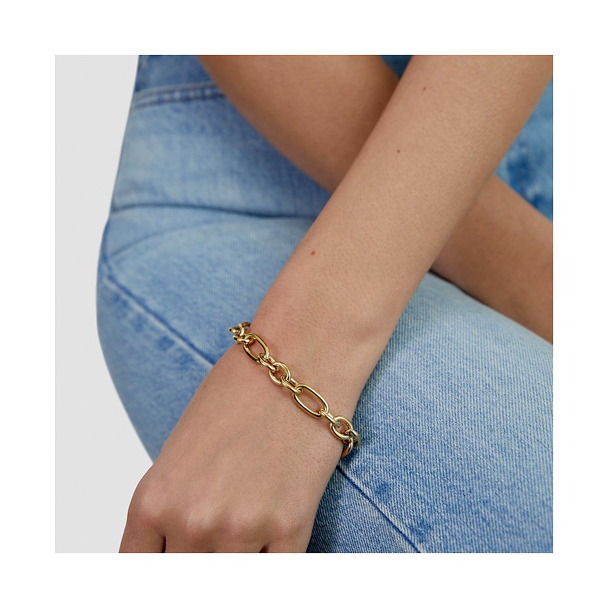 Goldfarbenes Tamaris Armband aus Edelstahl mit großen ovalen Gliedern am Handgelenk einer Person mit Jeanshose.