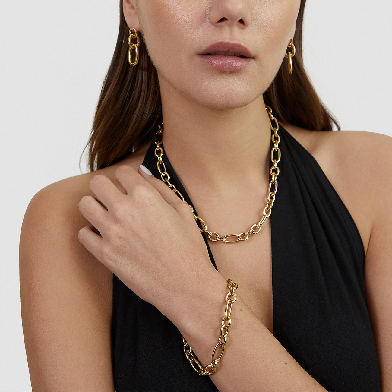 Eine Frau trägt passende Tamaris Ohrringe, eine Halskette und ein Armband aus goldfarbenem Edelstahl.
