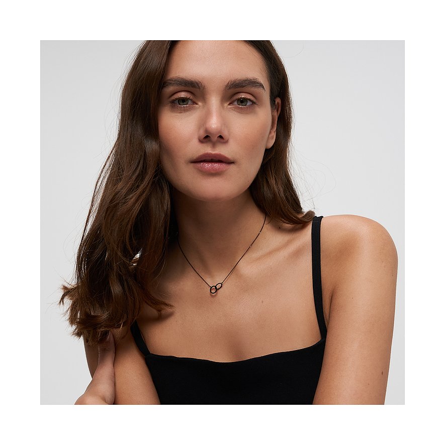 Primo piano di una donna che indossa una collana Tamaris in acciaio inox con pendente a infinito. Scatto ravvicinato.