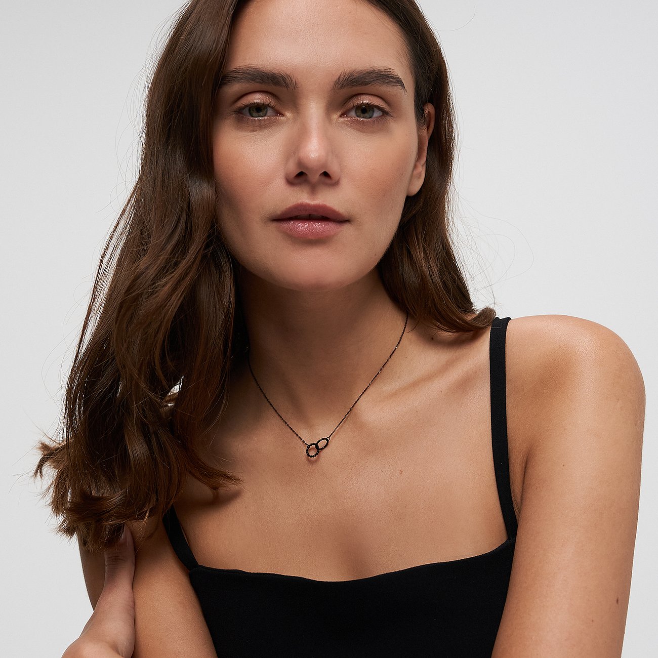 Primo piano di una donna che indossa una collana Tamaris in acciaio inox con pendente a infinito. Scatto ravvicinato.