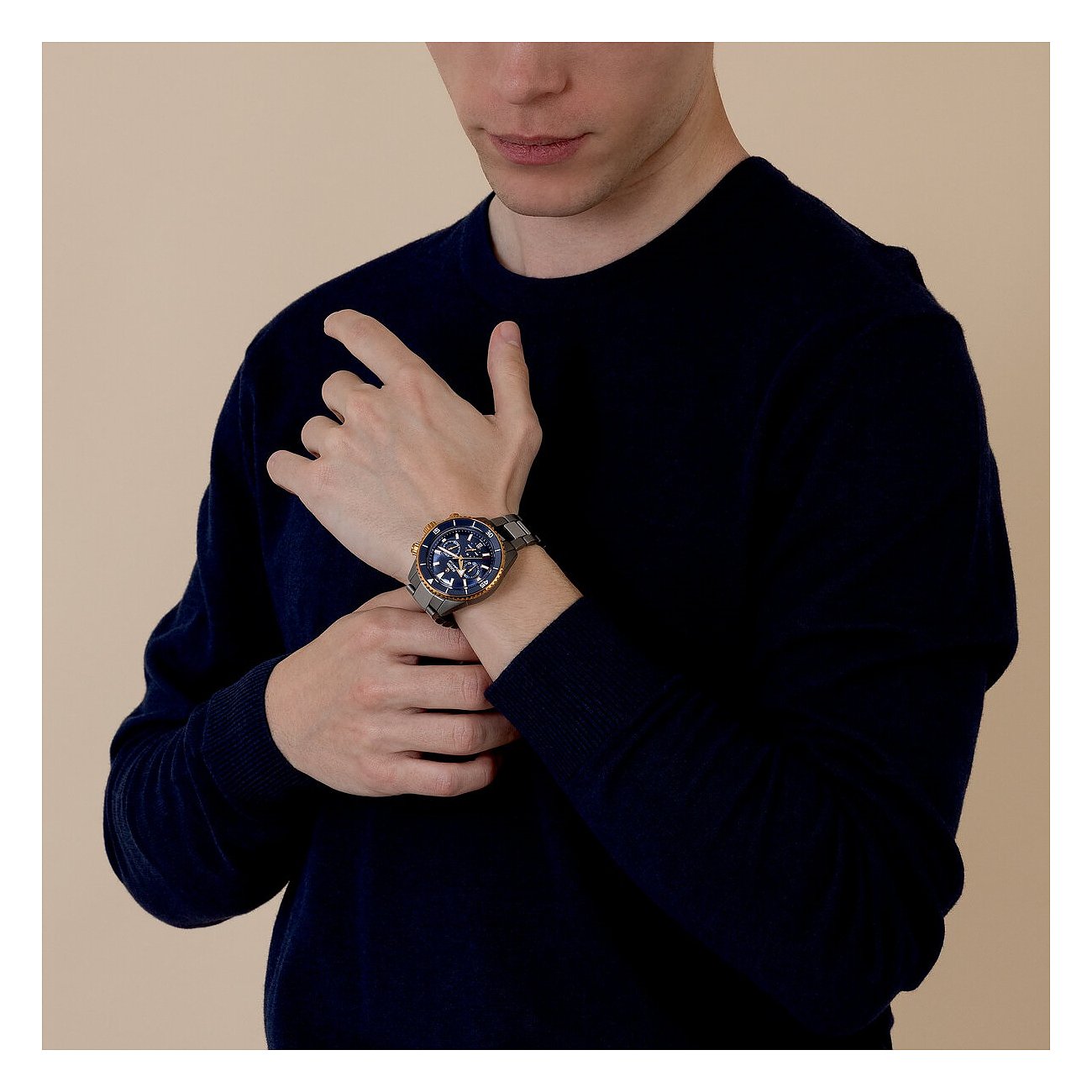 Ein Mann trägt eine Rado Herrenuhr aus blauem und goldenem Keramik am Handgelenk und hält seinen Arm.