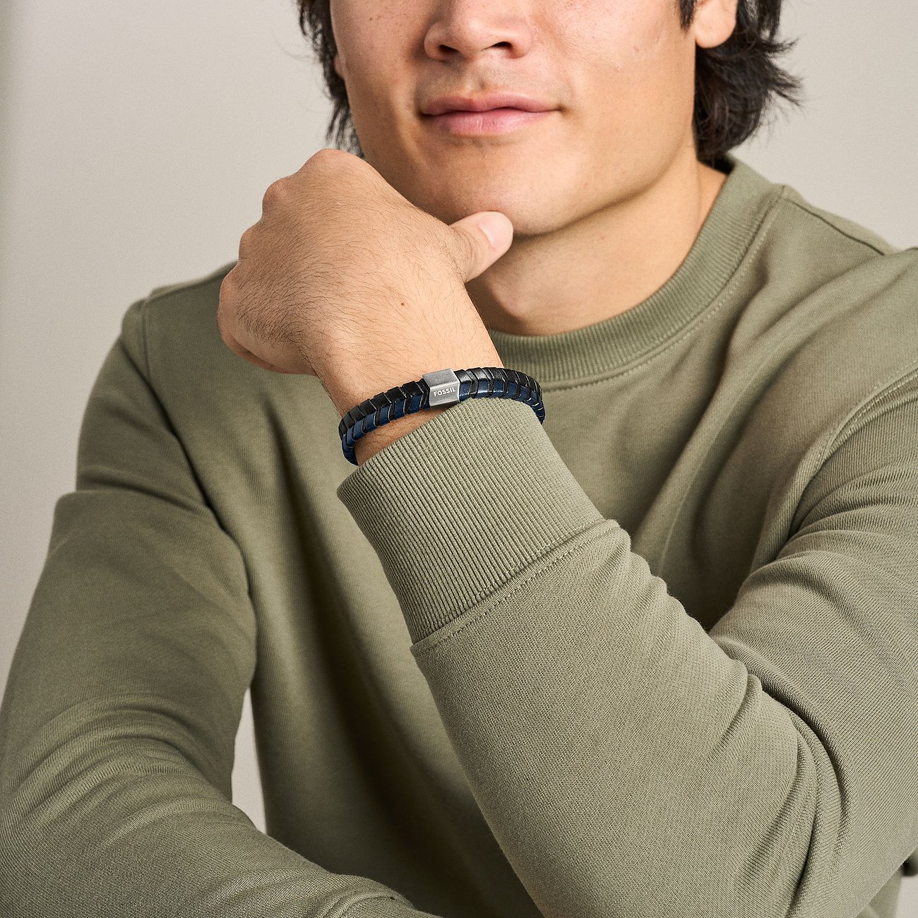 Ein Mann trägt ein blaues Fossil Armband aus Leder und Edelstahl mit quadratischem Verschluss am rechten Handgelenk.