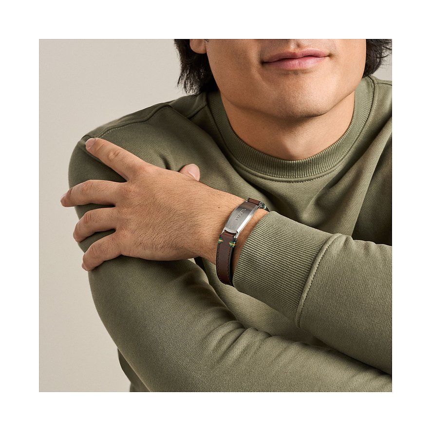 Ein Mann trägt ein Armband von Fossil aus braunem Leder und Edelstahl am linken Handgelenk.