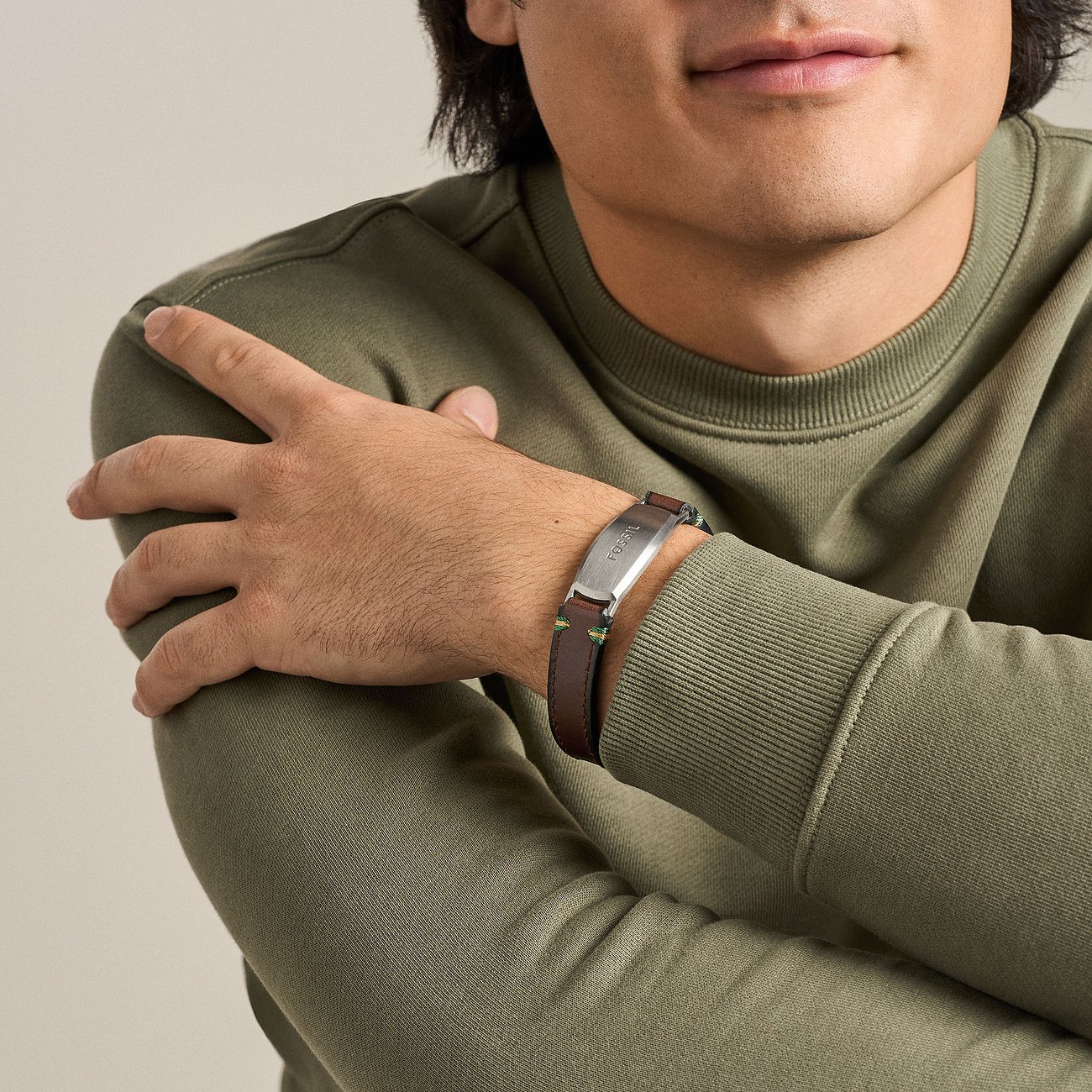 Ein Mann trägt ein Armband von Fossil aus braunem Leder und Edelstahl am linken Handgelenk.