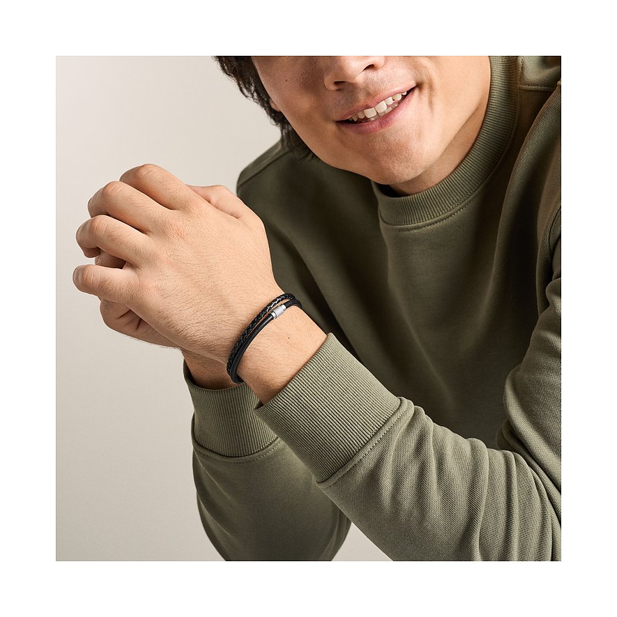 Lächelnder Mann trägt Fossil Armband aus geflochtenem schwarzem und braunem Leder mit Edelstahlverschluss am Handgelenk.