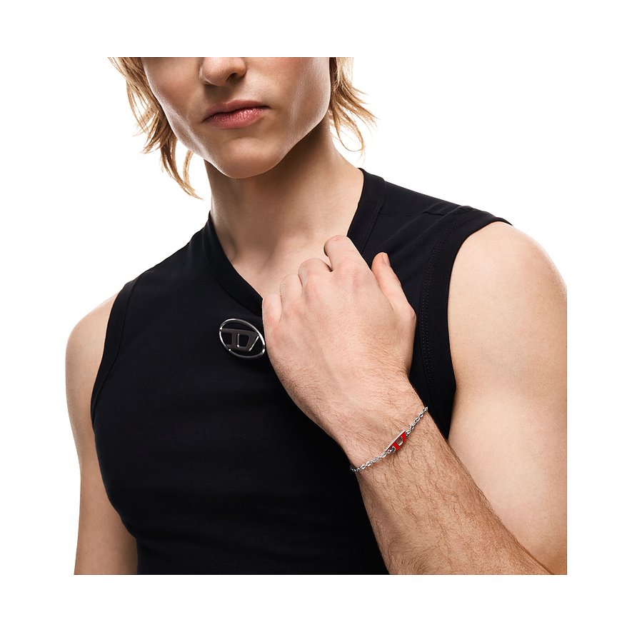 Mannequin trägt ein Diesel Armband aus Edelstahl mit roter Emaille auf einem feinen Kettenglied um sein rechtes Handgelenk.