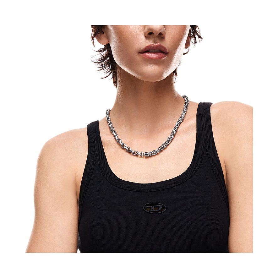 Le modèle porte un collier Diesel en acier inoxydable et émail avec maillons entrelacés.