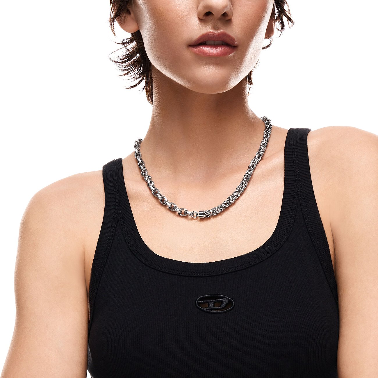 Le modèle porte un collier Diesel en acier inoxydable et émail avec maillons entrelacés.