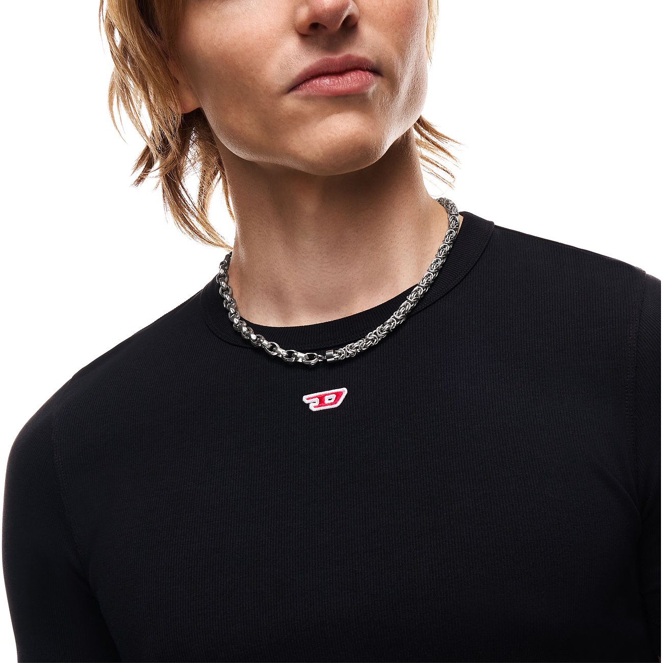 Gros plan d'une personne portant un collier Diesel Königskette en acier inoxydable autour du cou.