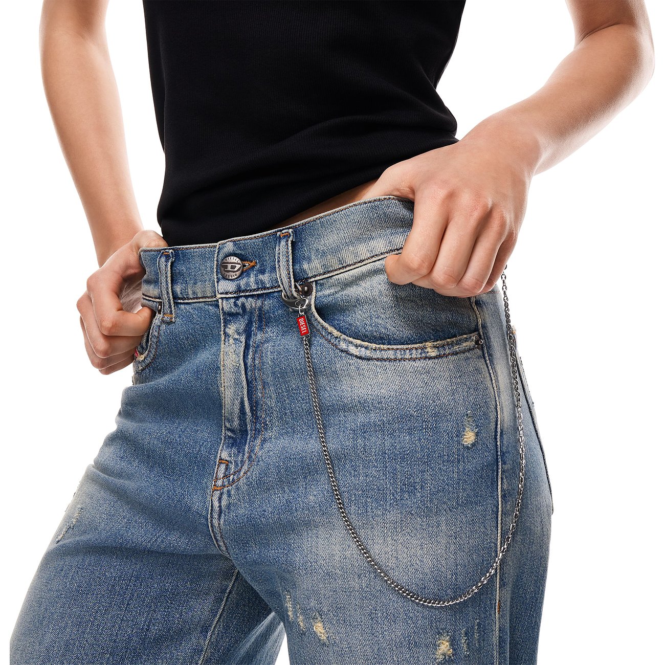 Nærbillede af en person iført Diesel-jeans med et halsmykke i rustfrit stål med emaljedetaljer som bæltekæde.