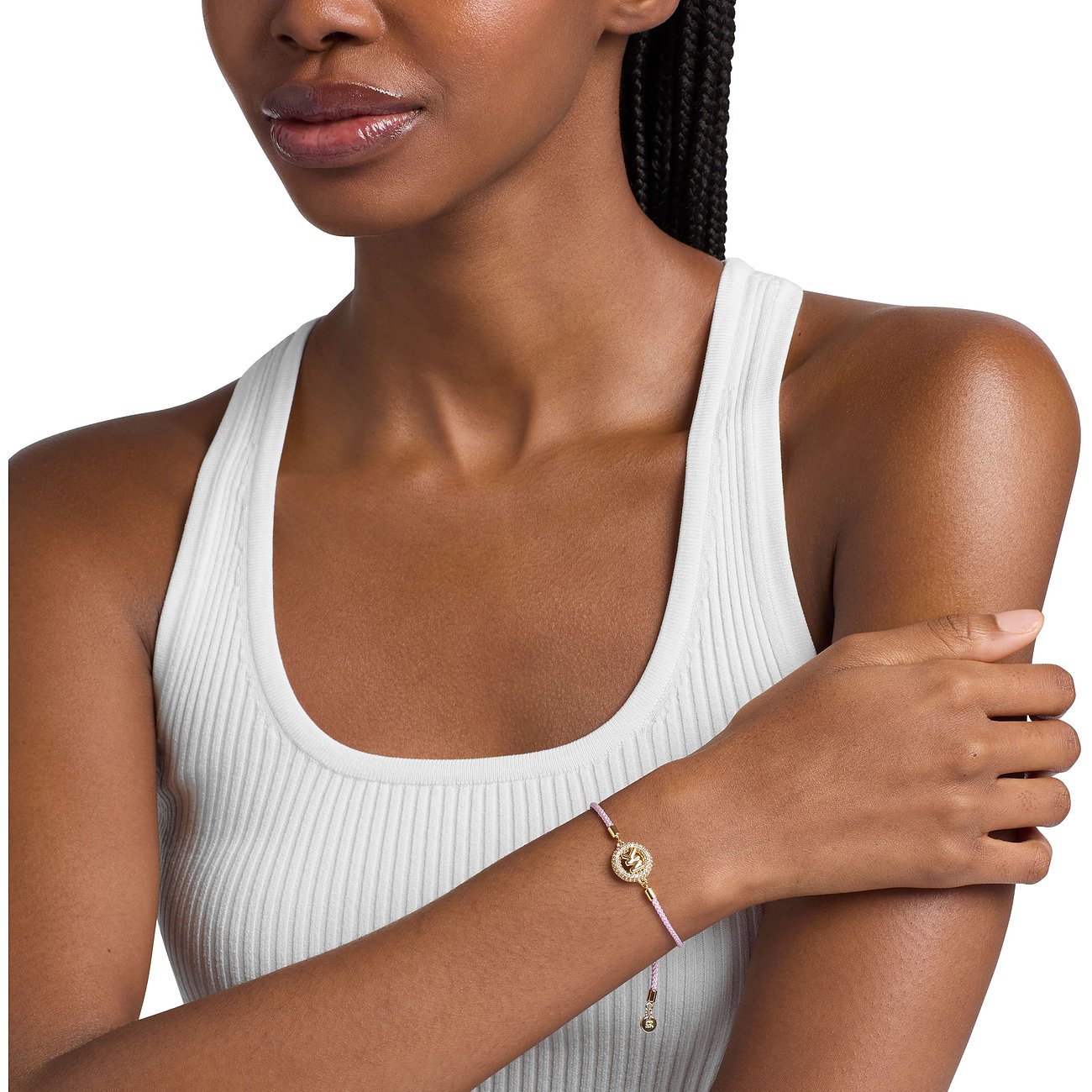 Eine Frau trägt das Michael Kors Armband aus goldfarbenem Metall mit leuchtend pinkem Band und Farbedelsteinen.