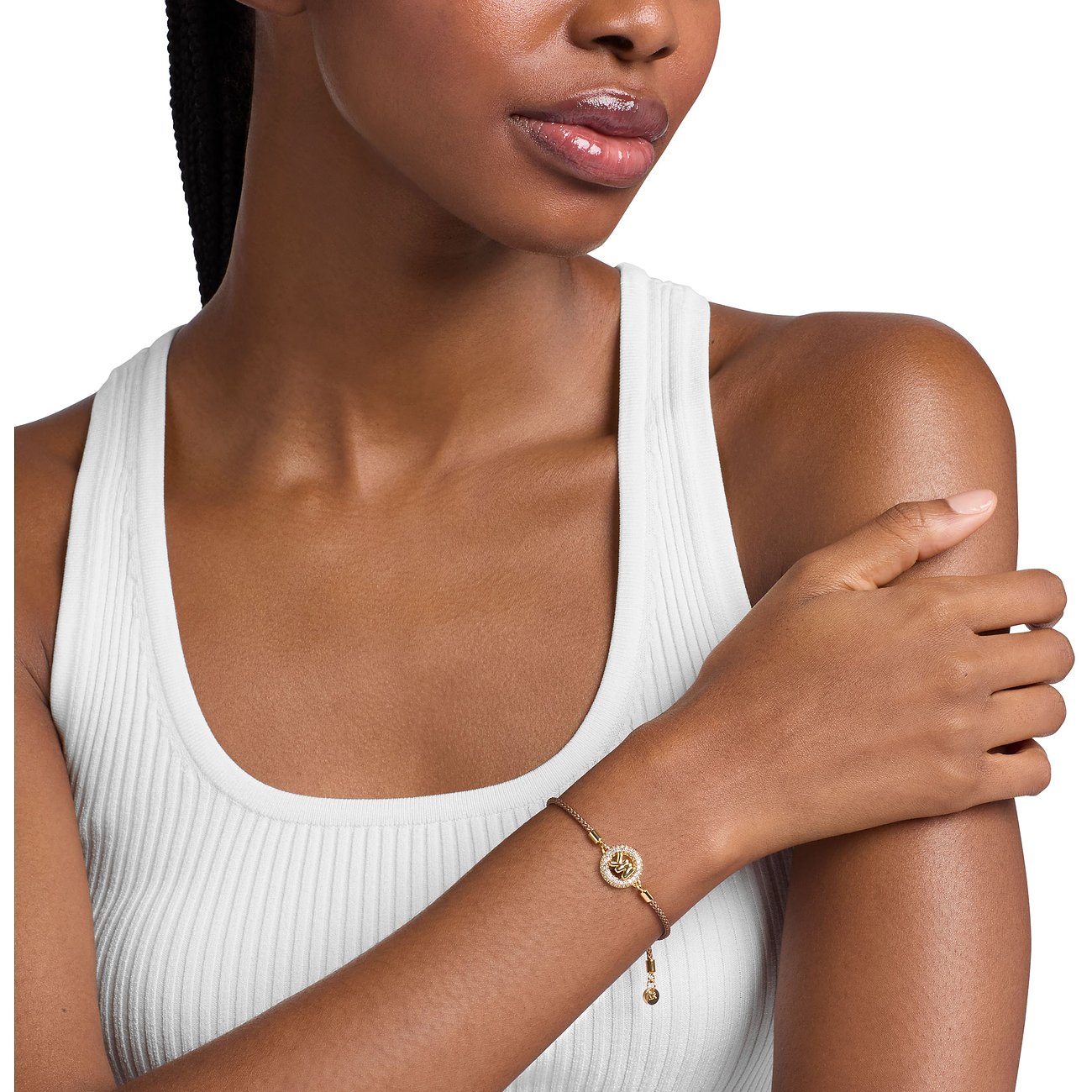 Am Arm einer Person sitzt ein Michael Kors Armschmuck aus Metall mit zwei Kugeln und einem runden Anhänger mit Zirkonia.