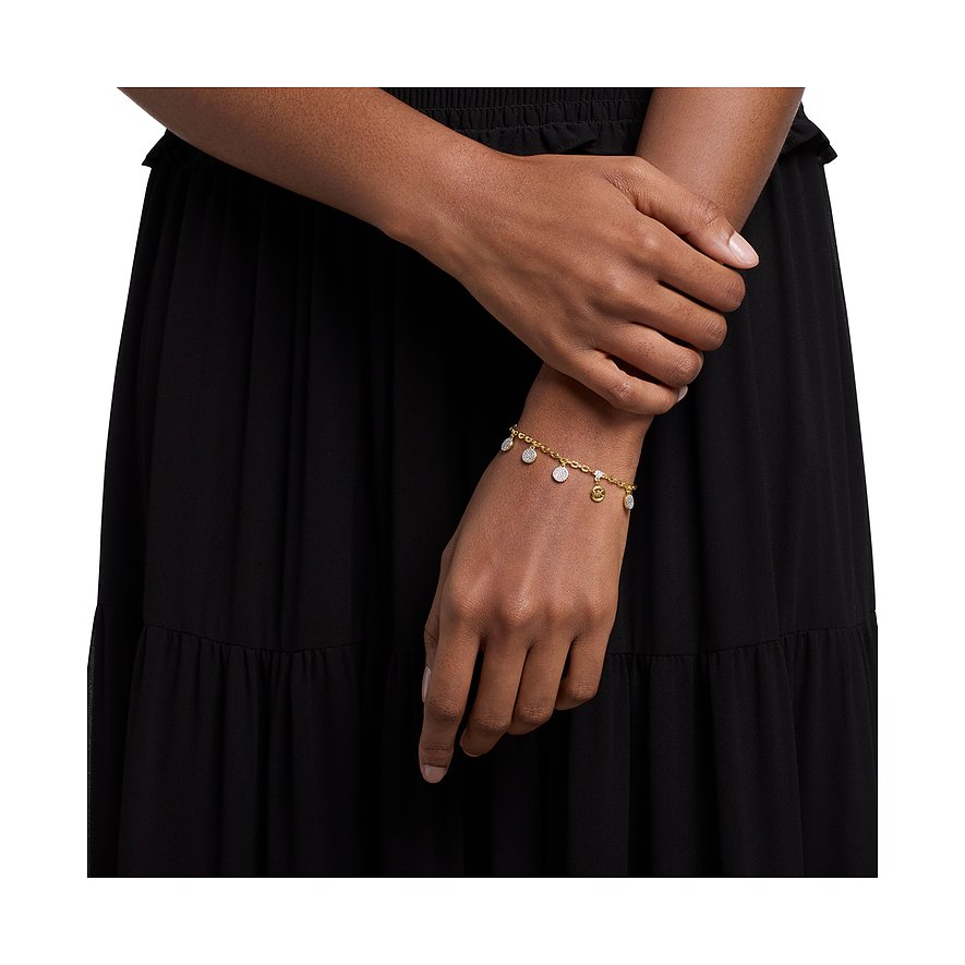 Am Handgelenk einer Person ein goldfarbenes Michael Kors Armband aus Metall mit glitzernden Zirkonia-Anhängern.