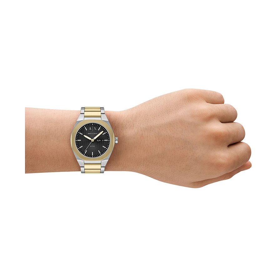 Armani Exchange Herrenuhr aus Edelstahl in Silber und Gold mit schwarzem Zifferblatt am Handgelenk getragen.