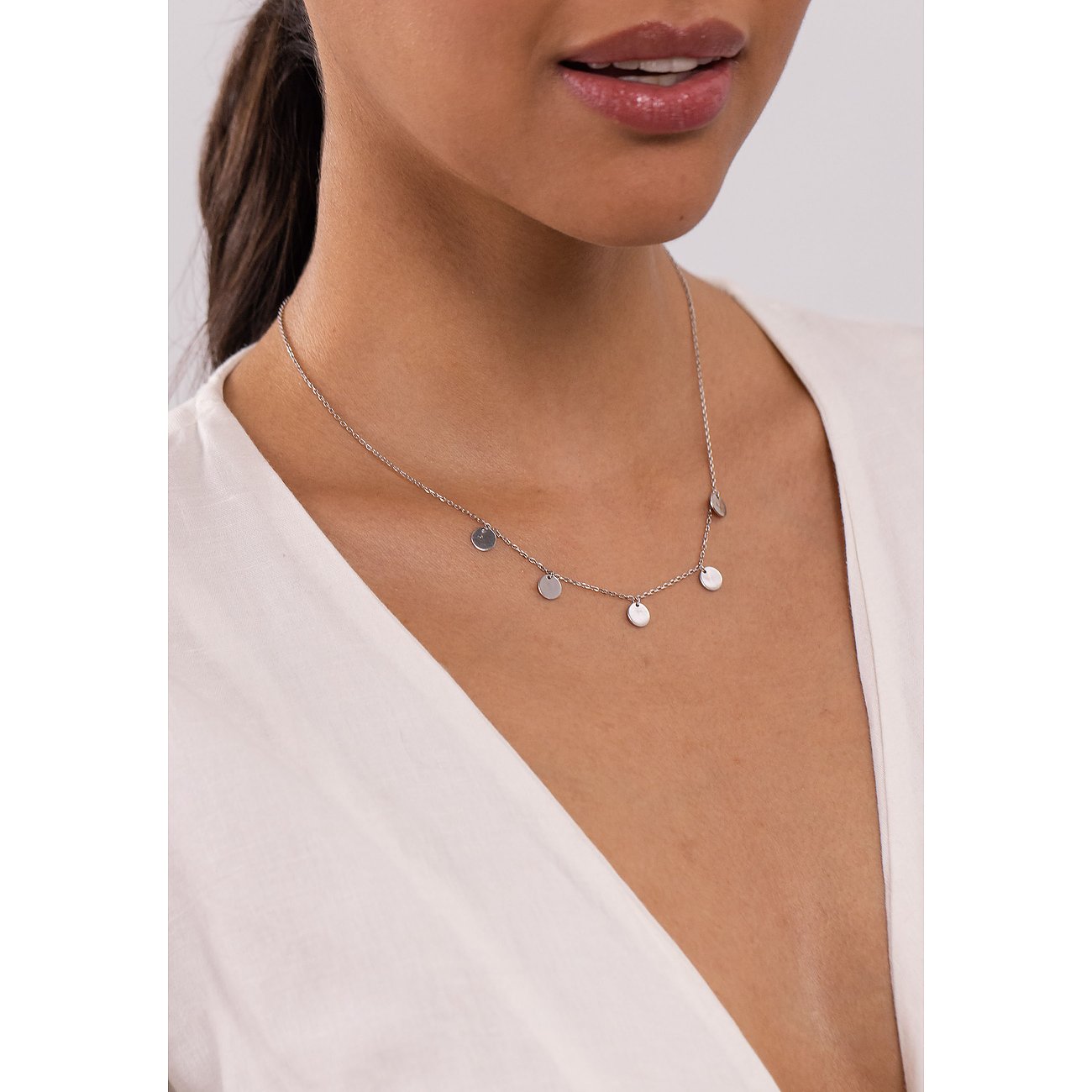 Een vrouw draagt de Purelei roestvrijstalen ketting met meerdere ronde hangers.