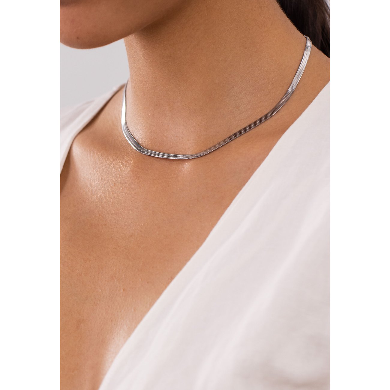 Femme portant un collier Purelei en acier inoxydable argenté, épousant élégamment son cou.
