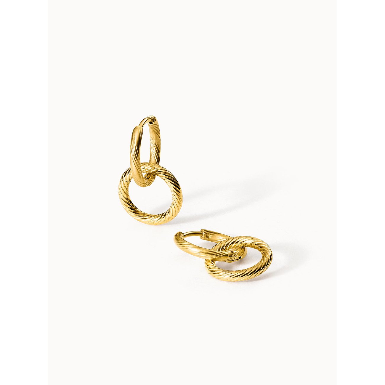 Zwei Purelei Edelstahl Ohrringe in Gold mit strukturierten Ringen, einer steht aufrecht, der andere liegt flach.