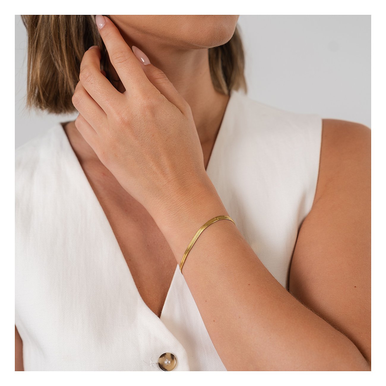 Am Handgelenk einer Frau getragen: ein goldenes Purelei Armband aus Edelstahl mit flacher Schlangenkette.