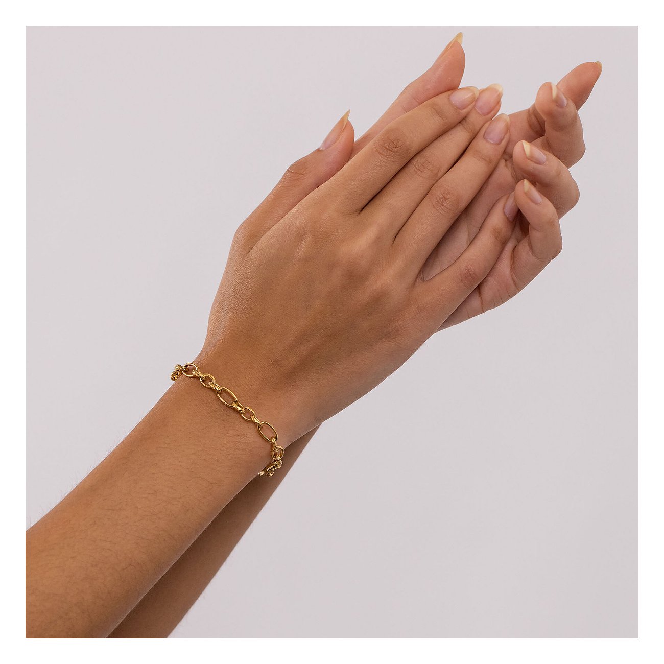 Eine Hand trägt ein goldenes Purelei Armband aus Edelstahl mit verschiedenen Gliedern.