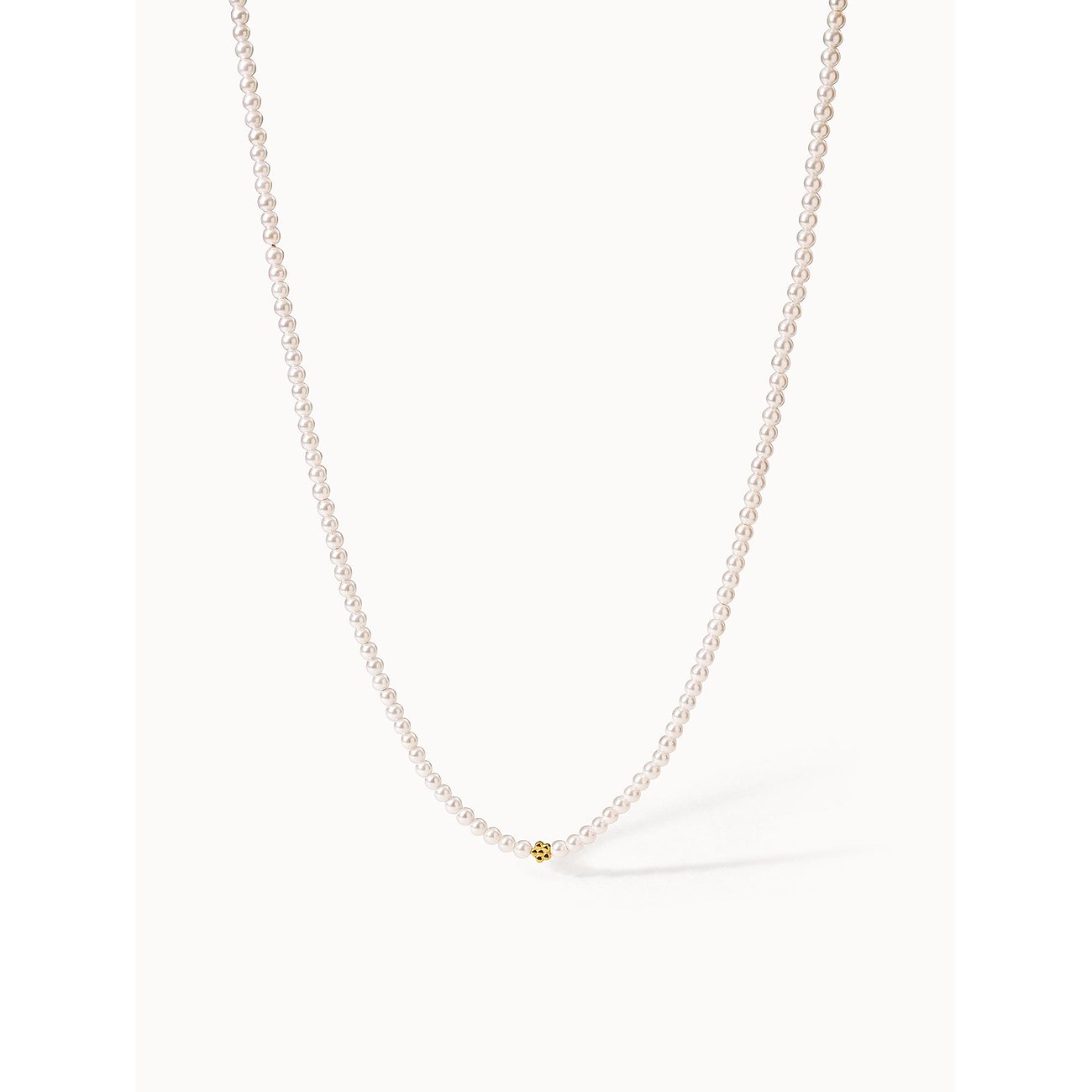 Een Purelei ketting van goudkleurig roestvrij staal met kleine parels en een enkele gouden parel in het midden.