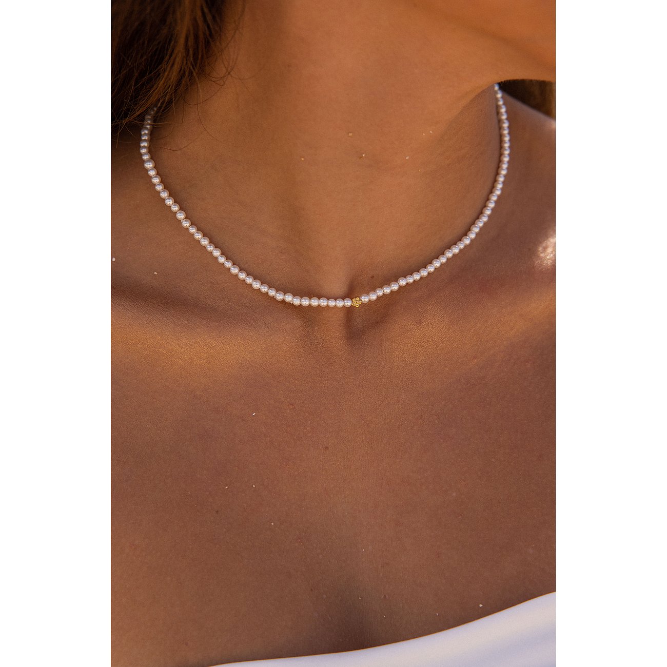 Close-up van een Purelei roestvrijstalen ketting met kleine parels en een enkel gouden accent in het midden.