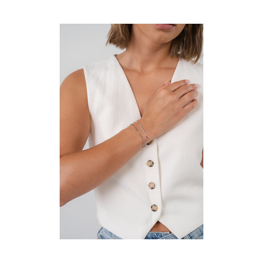 Een vrouw draagt een Purelei roestvrijstalen armband, bestaande uit twee fijne kettingen, elegant om haar pols.