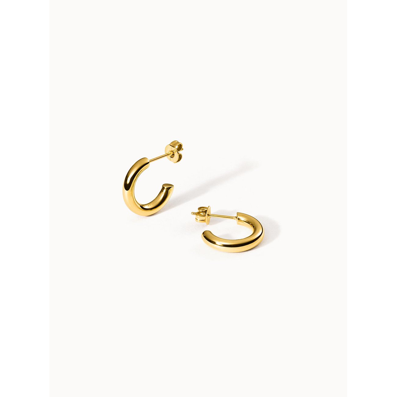 Ein Paar glänzende goldfarbene Ohrschmuck von Purelei aus Edelstahl, schlicht und elegant in C-Form.