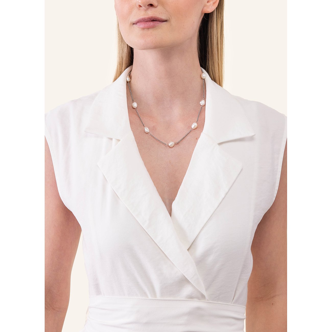 Een vrouw draagt een zilverkleurige Purelei roestvrijstalen ketting met elegante parels.