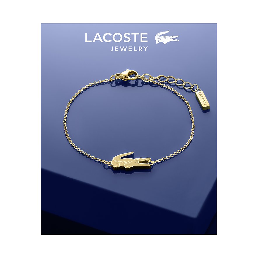 Lacoste armband van goudkleurig roestvrij staal met krokodilsymbool op marineblauwe achtergrond.
