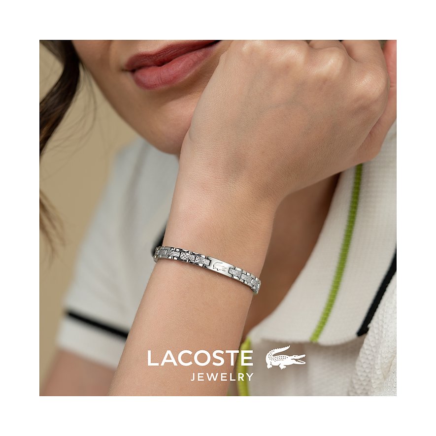 Close-up van een Lacoste roestvrijstalen armband om de pols van een model, met prominent merklogo vooraan.