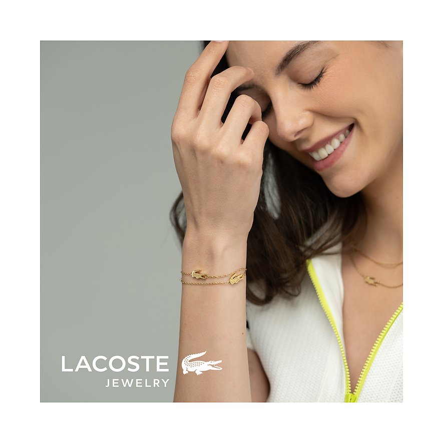 Een mooie vrouw draagt een gouden roestvrijstalen Lacoste armband met het kenmerkende krokodillenlogo.