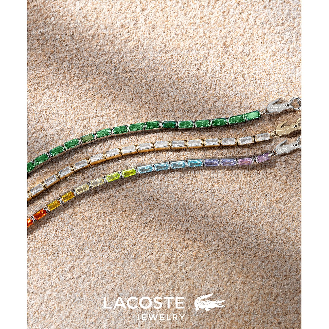 Drie Lacoste RVS armbanden met gekleurde zirkoniasteentjes in groen, wit en een kleurverloop.