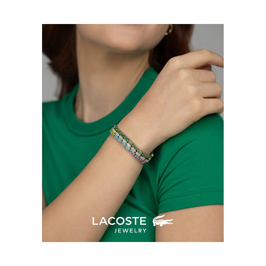 Aan de arm van iemand is een Lacoste armband te zien, van meerrijig roestvrij staal met gekleurde zirkoniasteentjes.