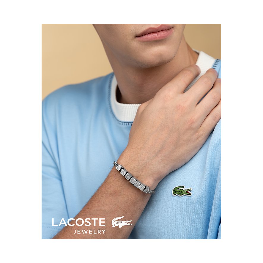 Nahaufnahme eines Mannes, der ein Lacoste Edelstahl Armband mit dem gravierten Schriftzug „Lacoste“ trägt.